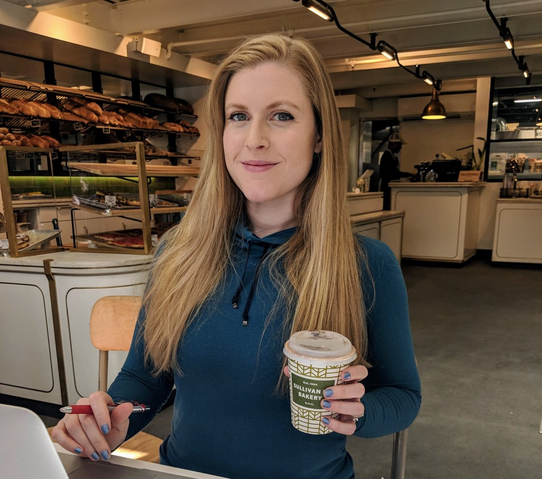 Fixing Fit Executive Editor Jenny Pierson editing at Sullivan Street Bakery in Hell's Kitchen, New York, holding a red pen.